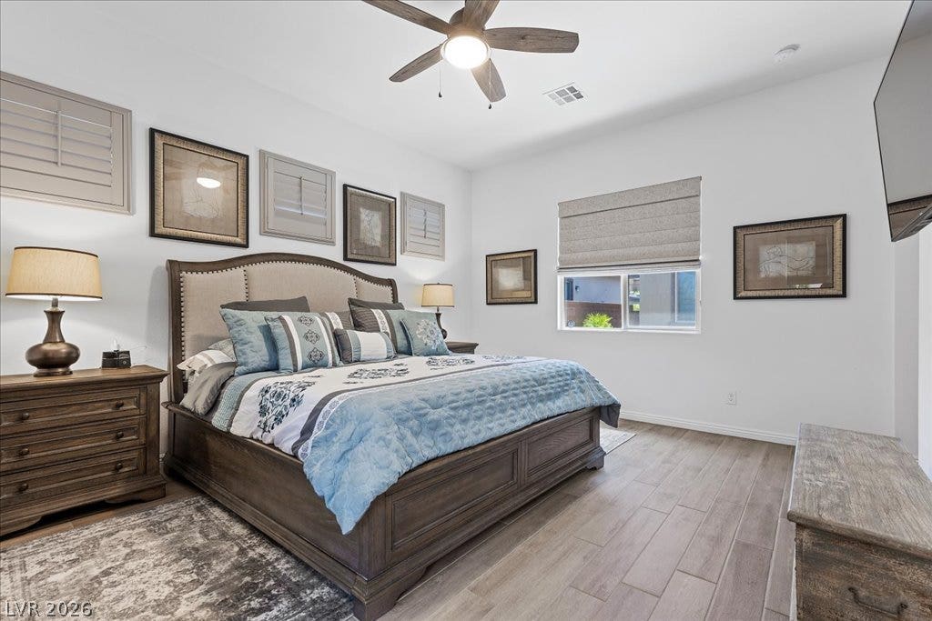 6722 Desert Crimson Street, Las Vegas, NV 89148 Gleaming wood-look floors and high ceilings define this welcoming primary bedroom retreat.