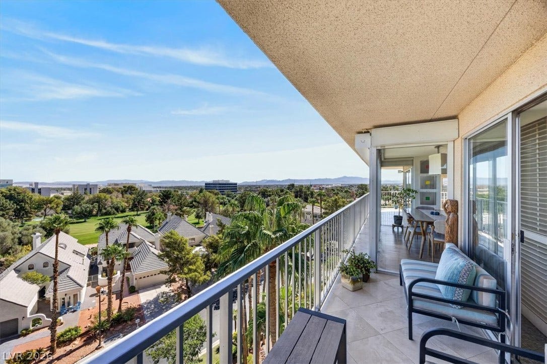 3111 Bel Air Drive, #7D, Las Vegas, NV 89109 An elevated private balcony overlooks neighborhood treetops and the distant mountain skyline under sunny skies.