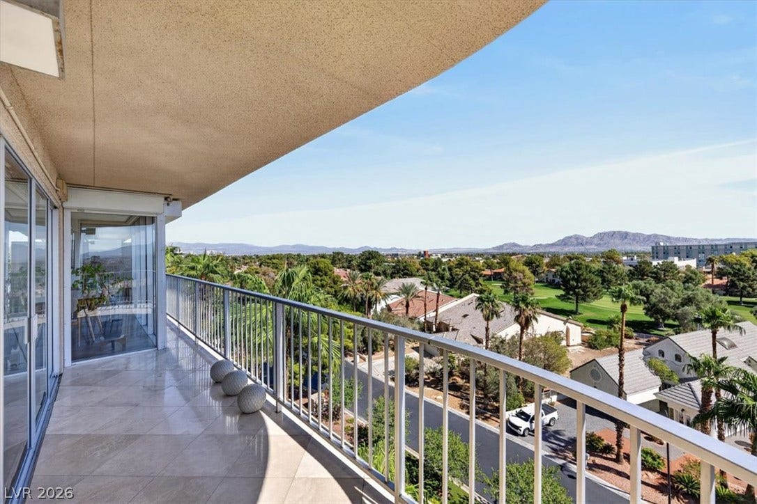 3111 Bel Air Drive, #7D, Las Vegas, NV 89109 An open balcony showcases extensive golf course and mountain views under clear blue skies.