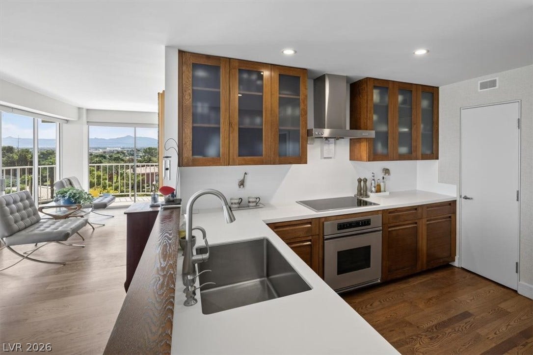 3111 Bel Air Drive, #7D, Las Vegas, NV 89109 Warm wood cabinetry and stone countertops frame a modern kitchen facing panoramic mountain views.