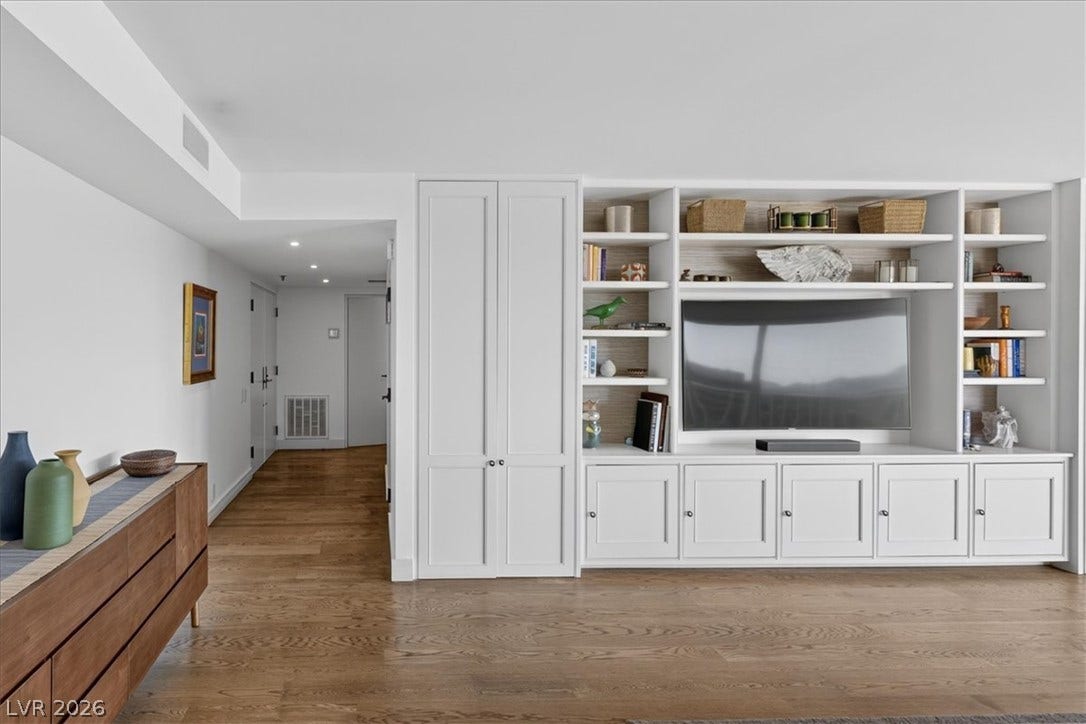 3111 Bel Air Drive, #7D, Las Vegas, NV 89109 Rich hardwood flooring anchors the living space, highlighted by expansive built-in shelving.