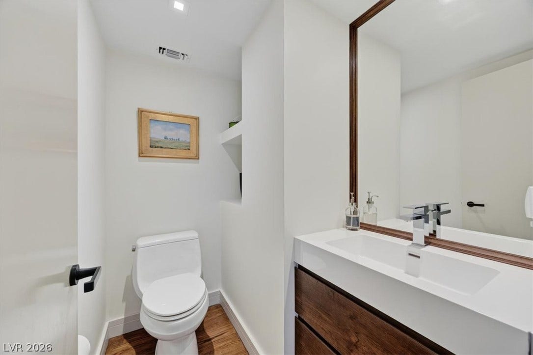 3111 Bel Air Drive, #7D, Las Vegas, NV 89109 Modern finishes define this minimalist powder room featuring warm wood-toned flooring and floating vanity details.