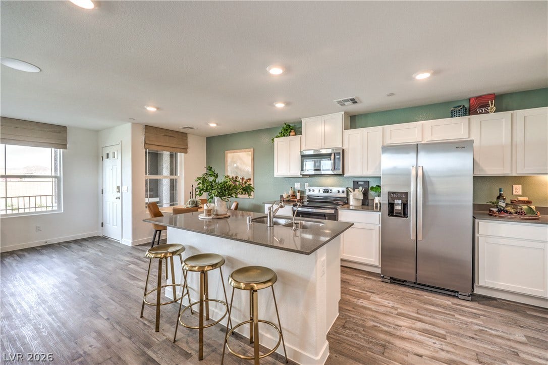 923 Black Heron Street, Henderson, NV 89011 Rich wood-look flooring and clean white cabinetry anchor this airy, open-concept kitchen.