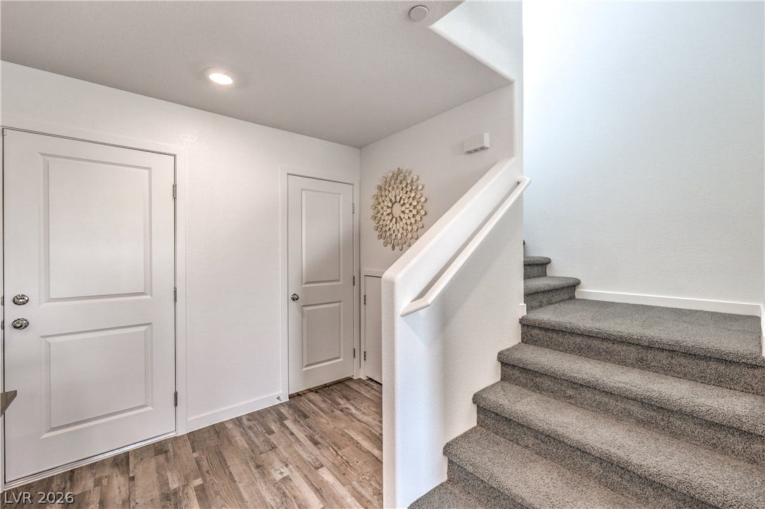 923 Black Heron Street, Henderson, NV 89011 A welcoming entryway transitions into wood-look flooring alongside carpeted stairs ascending upward.