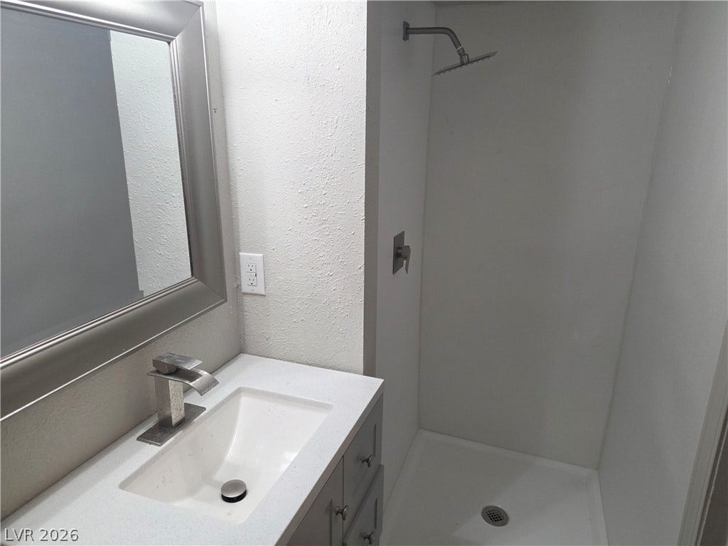 4364 Calimesa Street, Las Vegas, NV 89115 Clean lines define this updated bathroom featuring a sleek stone vanity and integrated walk-in shower.