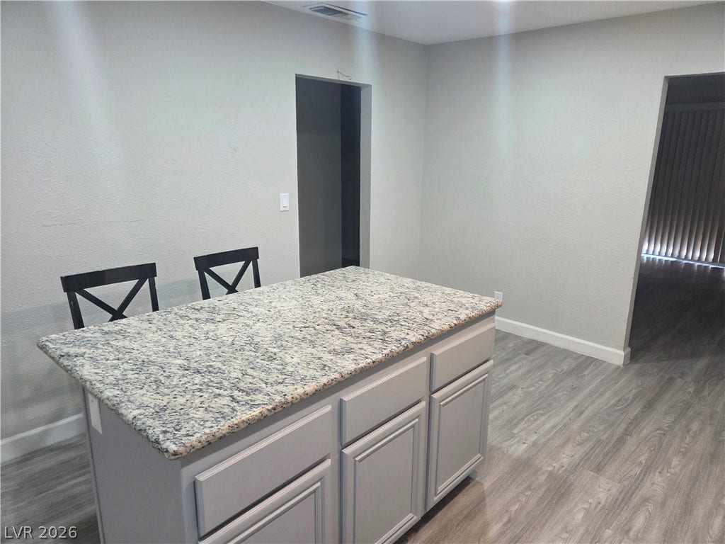 4364 Calimesa Street, Las Vegas, NV 89115 A stone-topped island centers this open kitchen area featuring durable wood-look flooring.