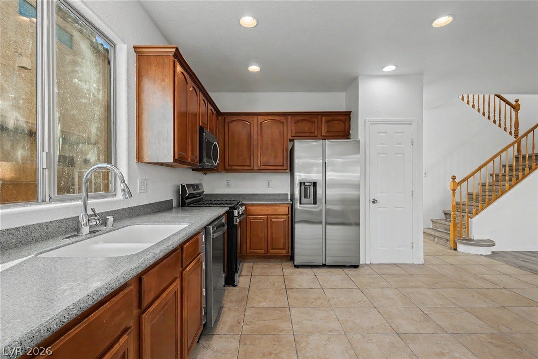 Warm wood cabinetry and durable stone counters define this functional cooking space near the stairs.