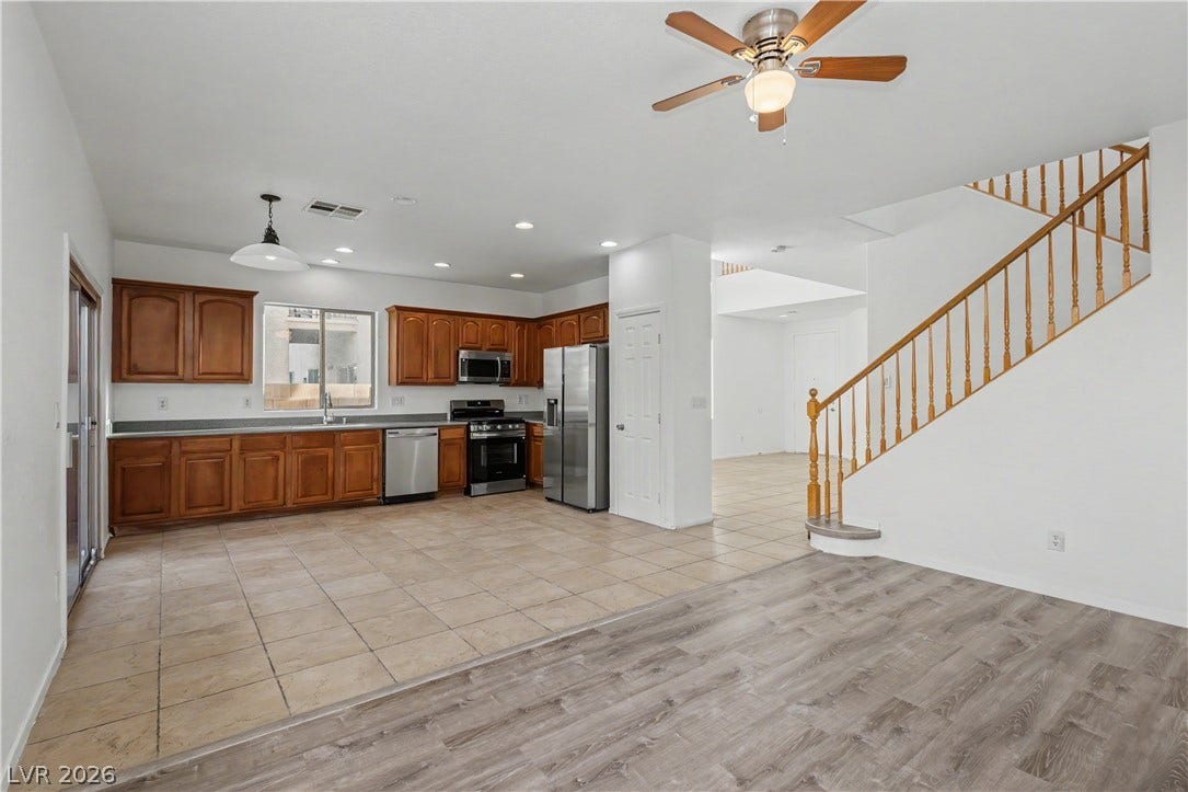 Tile and wood-style flooring flow through this open-concept layout with a prominent wooden staircase.