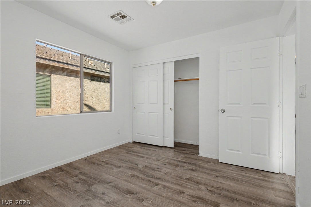 Durable plank flooring and a wide window define this comfortable secondary bedroom.