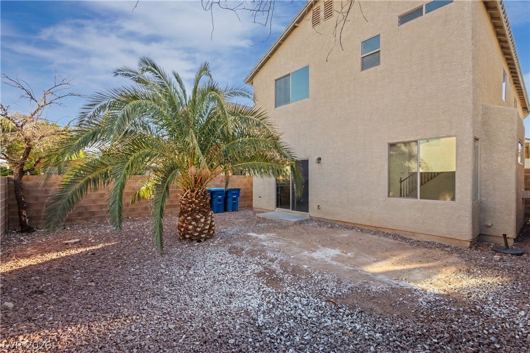 A spacious backyard area includes a gravel ground cover alongside a low-maintenance concrete patio.