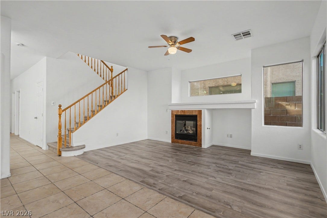 An open living space showcases dual flooring types alongside a built-in fireplace and wooden staircase.