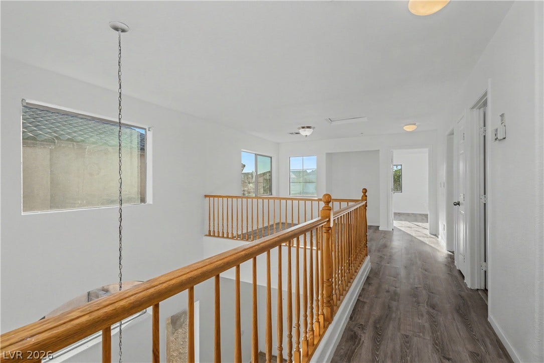 An open upper level features wood railings and classic vinyl flooring.