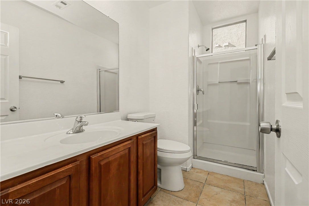 A glass-enclosed walk-in shower and wood vanity highlight this clean bathroom space.