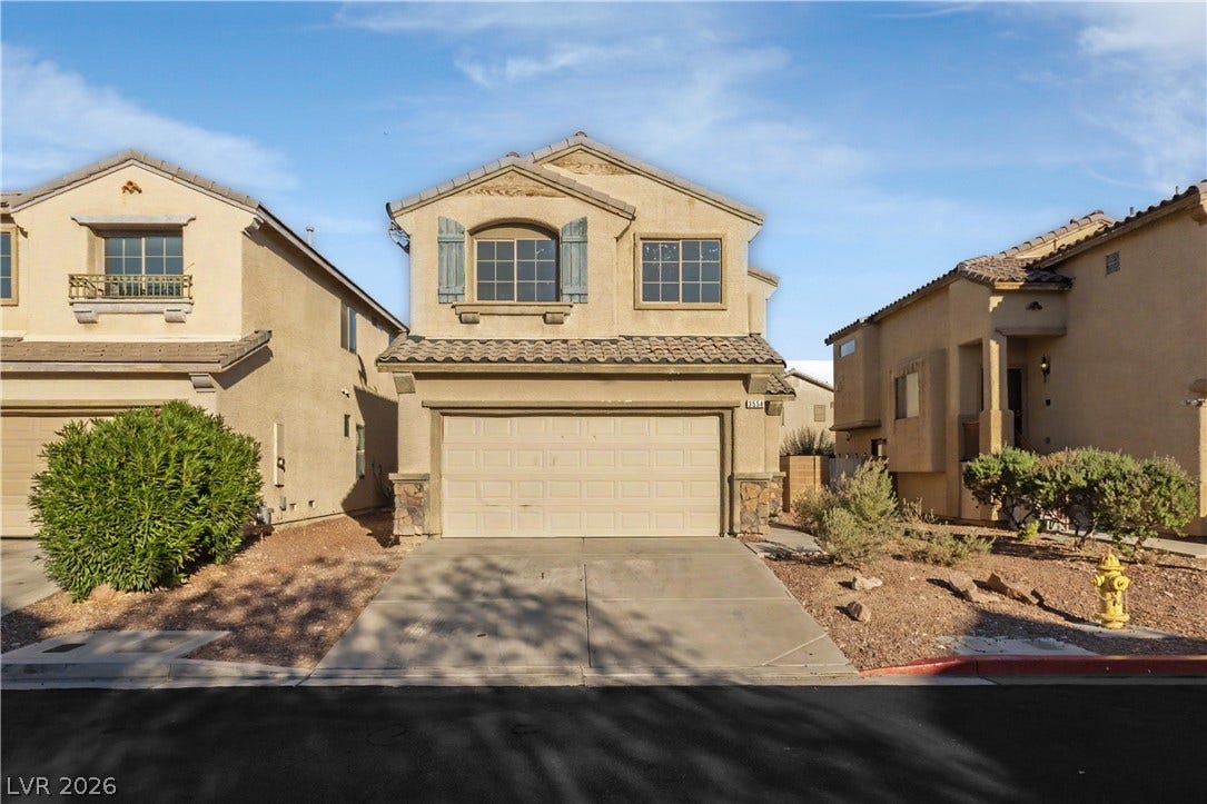 An inviting exterior displays classic desert architecture with structured stone accents and concrete driveway.