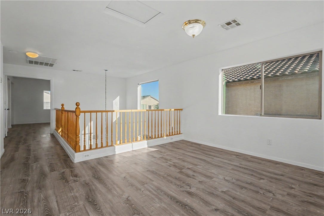 Clean wood-look flooring and a classic wooden balustrade define this versatile upper-level loft space.