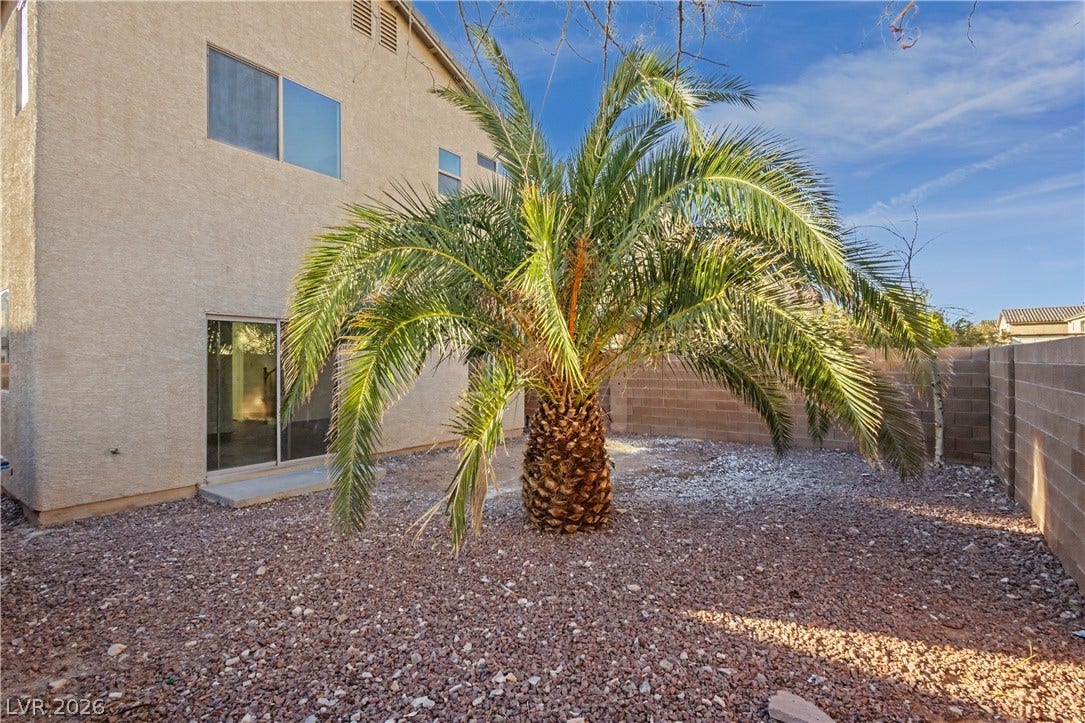 A private backyard features stucco exteriors and gravel ground cover framed by block fencing.