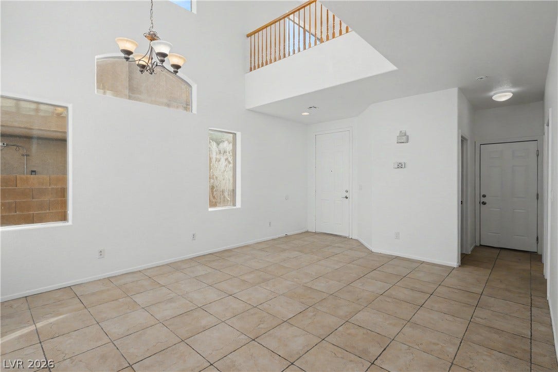 A soaring two-story ceiling and neutral tile flooring define this airy entryway.