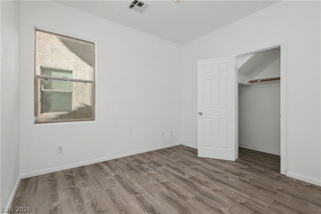 Rich wood-look flooring and crisp plaster walls define this versatile secondary bedroom space.