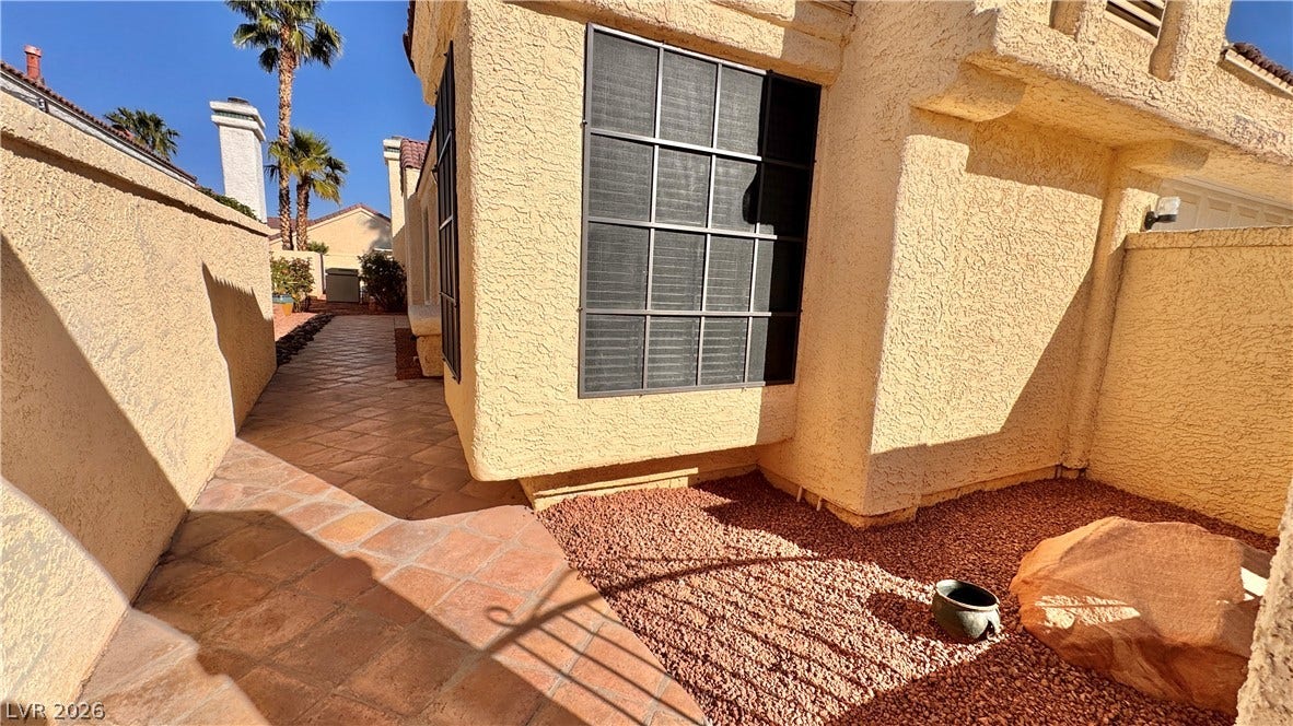 5236 Crooked River Circle, Las Vegas, NV 89149 A tiled walkway winds alongside the stucco exterior under clear blue skies.
