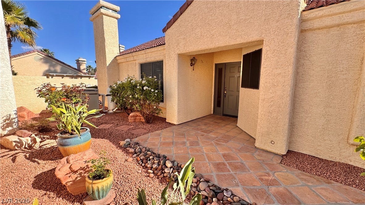 5236 Crooked River Circle, Las Vegas, NV 89149 A tiled walkway leads to the recessed entryway of this Spanish-style stucco home.