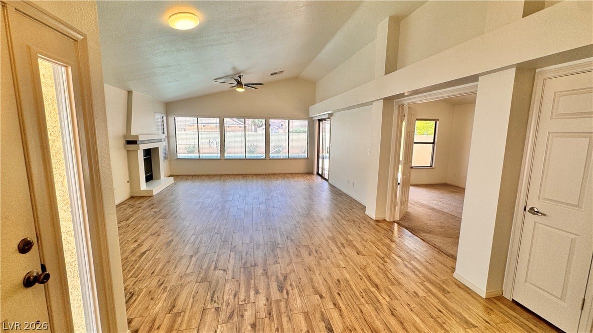 5236 Crooked River Circle, Las Vegas, NV 89149 A spacious living room features polished wood-look floors under a soaring vaulted ceiling.