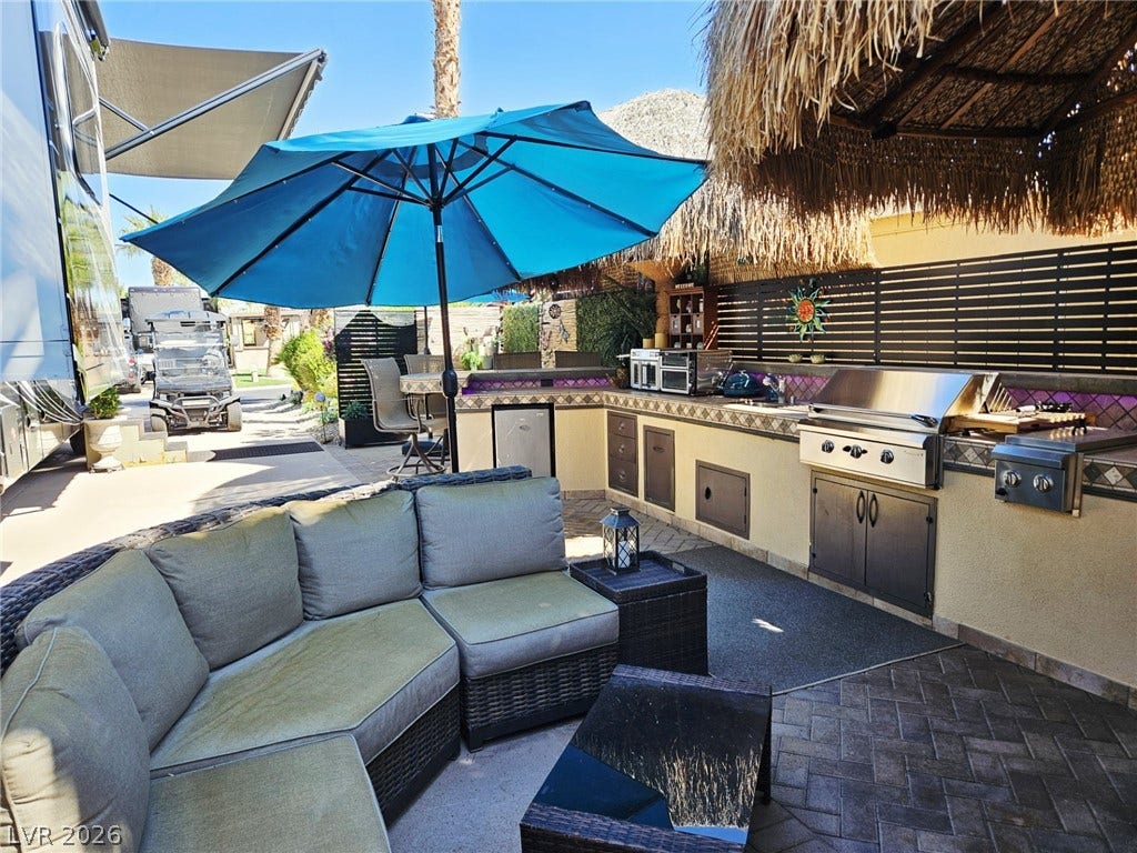 8175 Arville Street, #305, Las Vegas, NV 89139 An outdoor kitchen with built-in barbecue and stone countertops coordinates under a thatched roof palapa.