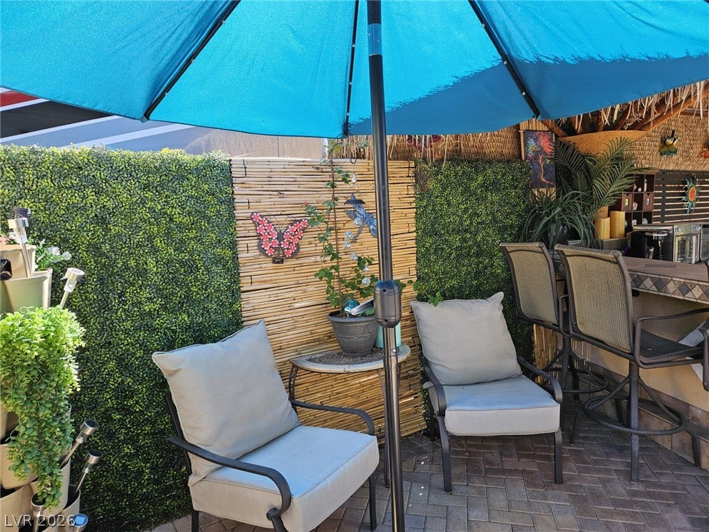 8175 Arville Street, #305, Las Vegas, NV 89139 Tiled flooring and privacy hedging define this inviting outdoor entertainment setup.