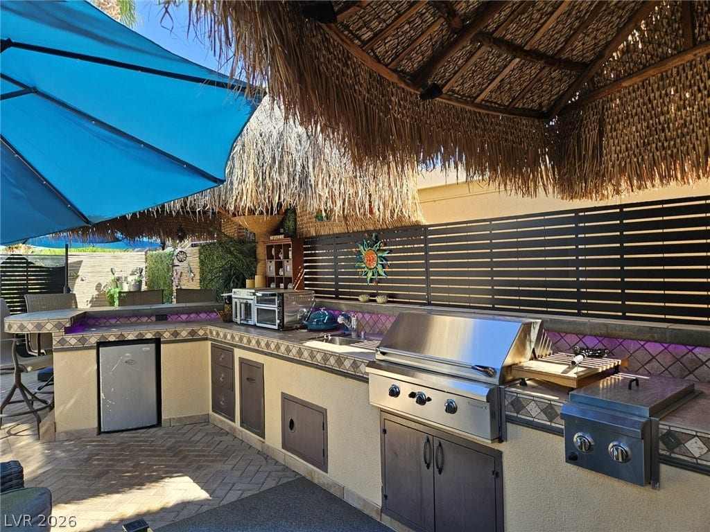 8175 Arville Street, #305, Las Vegas, NV 89139 An outdoor kitchen features tiled countertops, stainless steel appliances, and a thatched roof cover.