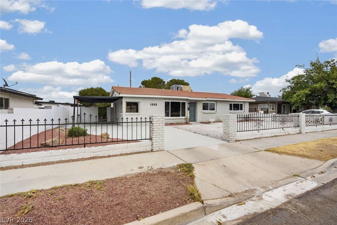 1669 N G Street, Las Vegas, NV 89106 Gated perimeter fencing borders the low-maintenance front yard of this single-story brick home.