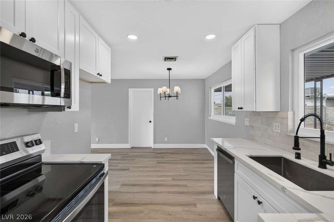 1669 N G Street, Las Vegas, NV 89106 Crisp white cabinetry paired with durable flooring defines this modernized cooking and dining area.