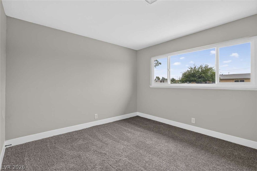 1669 N G Street, Las Vegas, NV 89106 Natural light streams through a wide window into this carpeted bedroom.