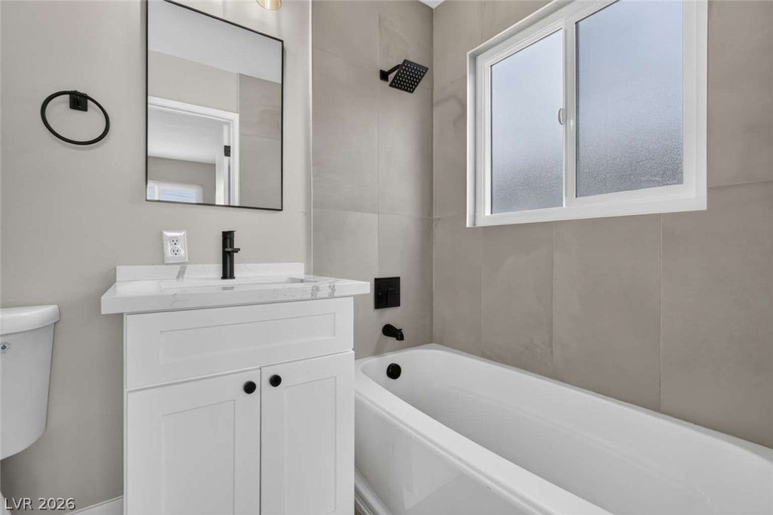 1669 N G Street, Las Vegas, NV 89106 A modern bathroom features a clean white vanity and a tiled tub surround.