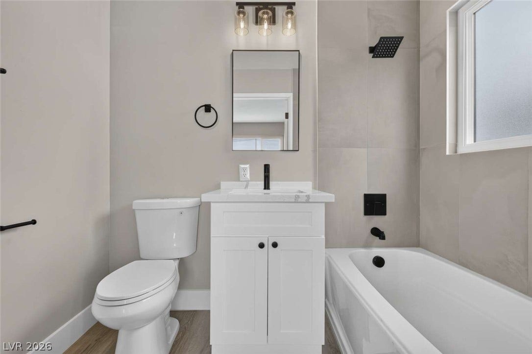 1669 N G Street, Las Vegas, NV 89106 Modern finishes define this bathroom featuring a tiled tub surround and a white vanity.