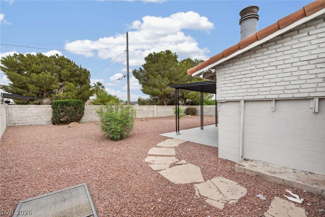 1669 N G Street, Las Vegas, NV 89106 A stone pathway leads across the low-maintenance gravel yard beside a covered patio area.
