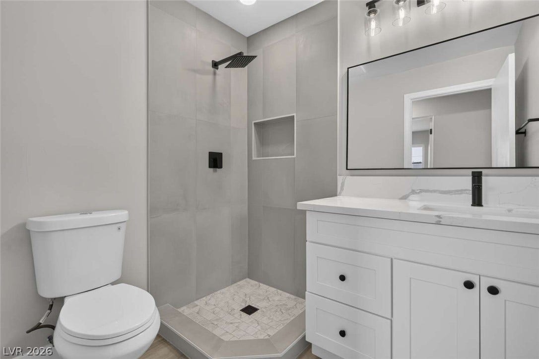 1669 N G Street, Las Vegas, NV 89106 Clean lines and stone counters highlight this modern bathroom with a tiled walk-in shower.