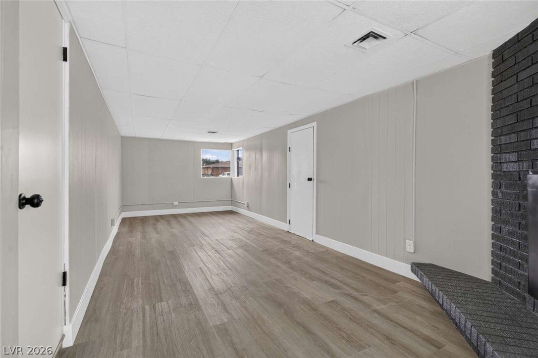 1669 N G Street, Las Vegas, NV 89106 Smooth wood-look flooring and a brick fireplace anchor this versatile finished lower level living space.