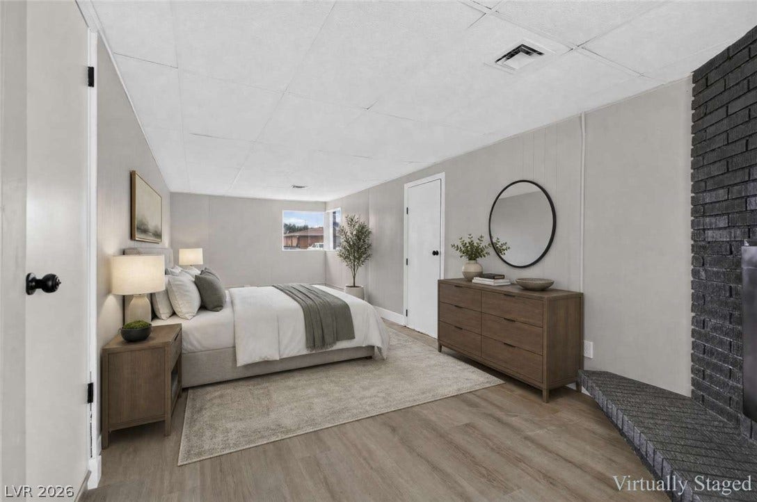1669 N G Street, Las Vegas, NV 89106 A brick fireplace anchors this bedroom space featuring wood-look flooring.