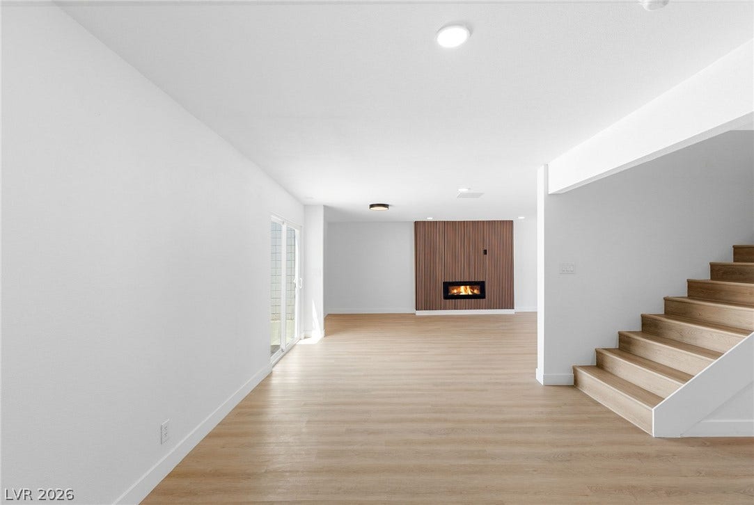 3471 One Nation Avenue, Las Vegas, NV 89121 A chic modern fireplace set into a wood-paneled wall creates a captivating focal point in this luminous open-plan living space.