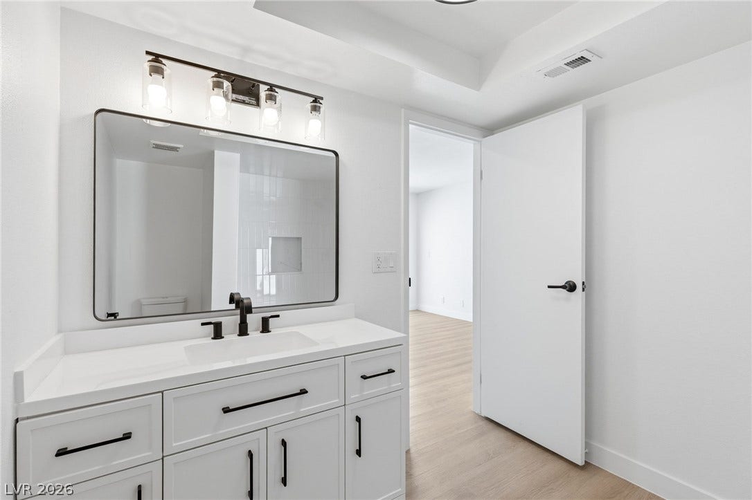 3471 One Nation Avenue, Las Vegas, NV 89121 Modern bathroom vanity with sleek hardware and a generous mirror, reflecting a clean shower interior.