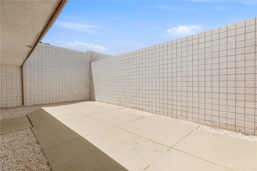 3471 One Nation Avenue, Las Vegas, NV 89121 A secluded patio retreat with minimalist tiled walls and paved flooring, ideal for private outdoor enjoyment.
