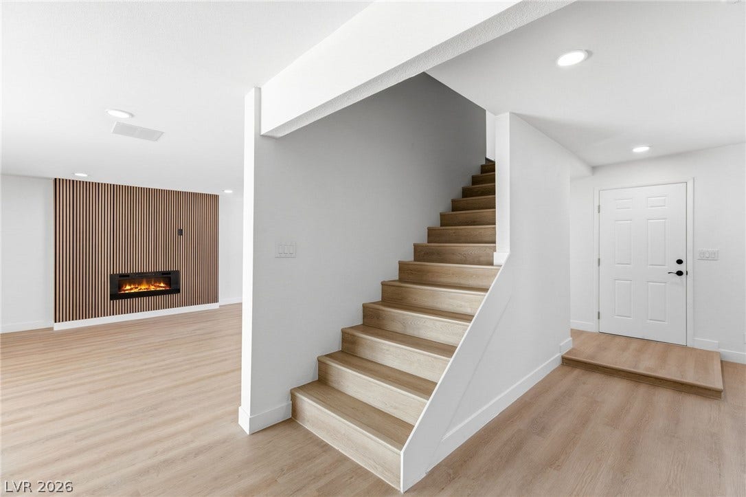 3471 One Nation Avenue, Las Vegas, NV 89121 A chic electric fireplace adds warmth to this inviting living space with sleek flooring and modern staircase.