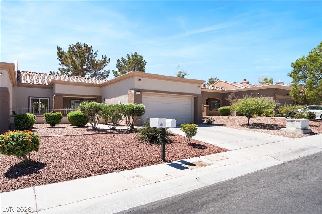 Desert landscaping and a concrete driveway lead to a classic tiled roof home.