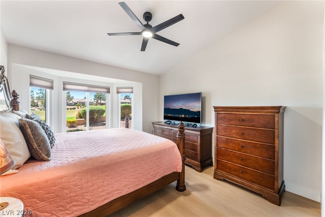 Hardwood floors and a wide bay window frame peaceful views in this comfortable bedroom.