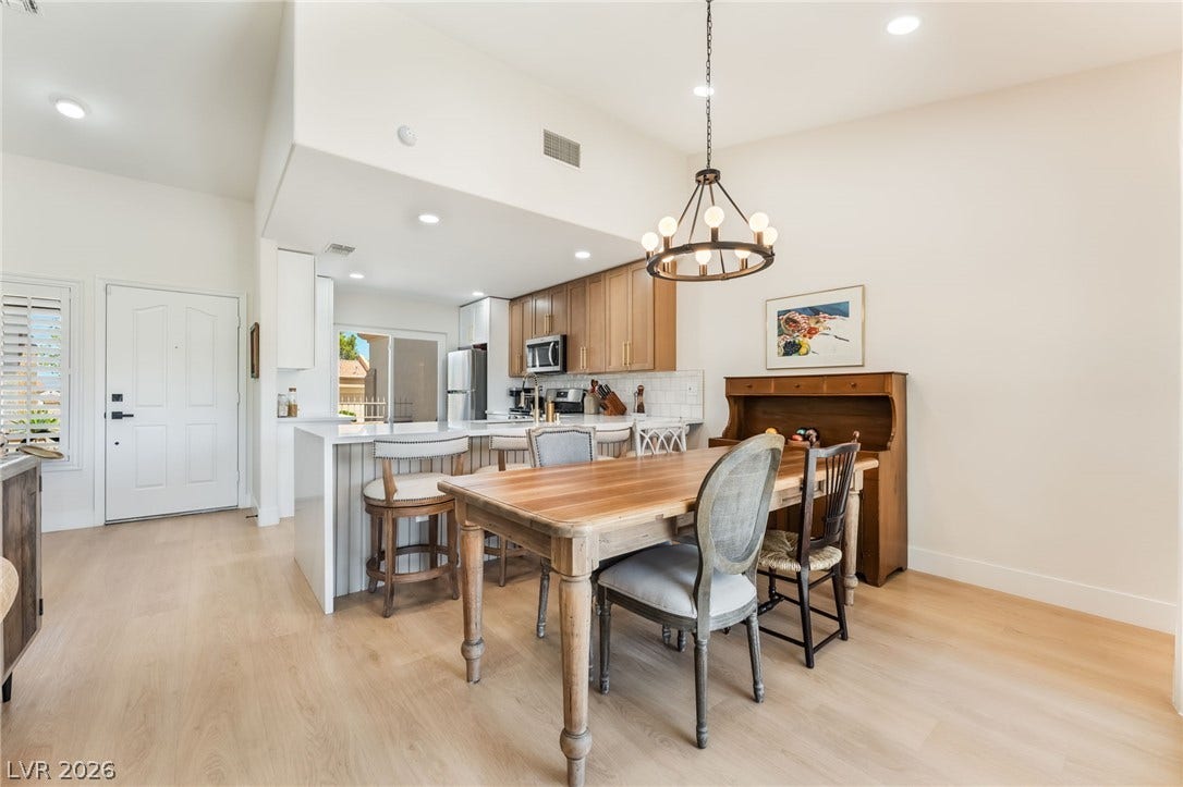 An open dining area flows seamlessly into the kitchen over light wood flooring.