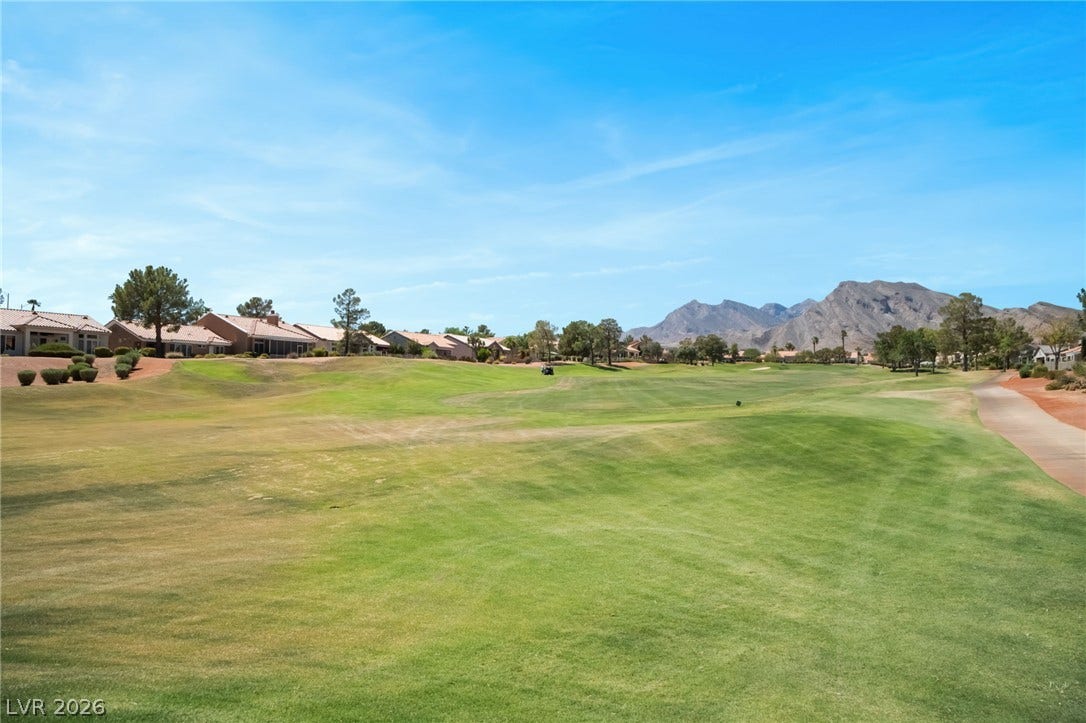 Rolling fairways border neighboring homes set against a dramatic mountain backdrop.