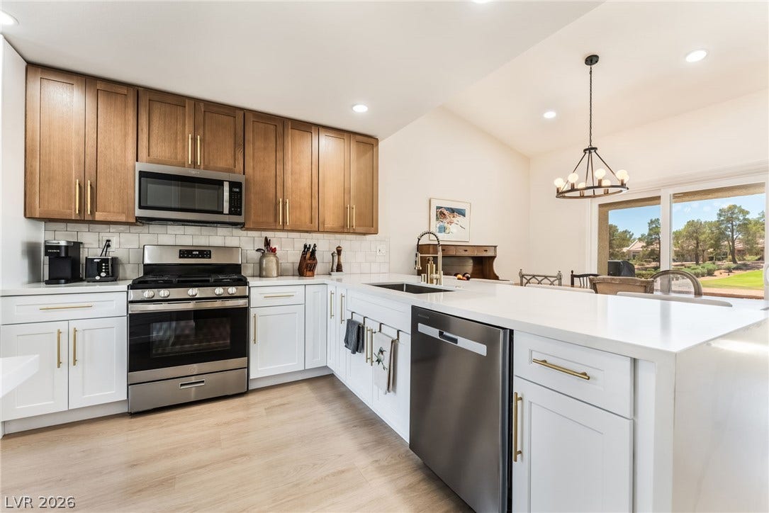 Bright modern kitchen features dual-tone cabinetry, premium stone countertops, and durable wood-look flooring.