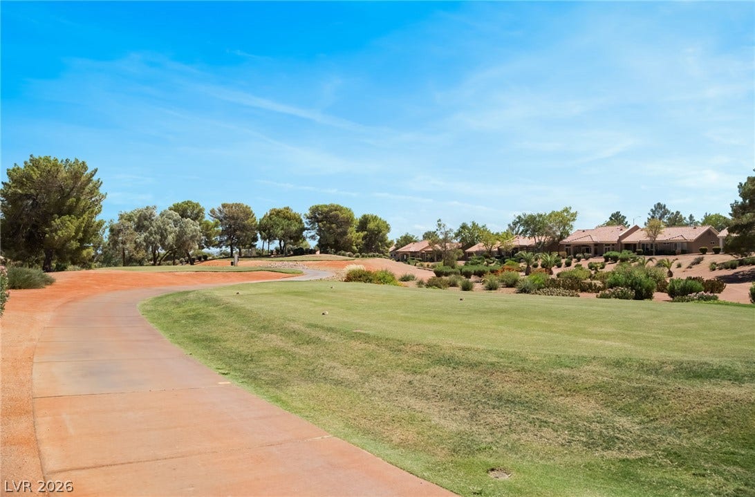 Manicured green fairways wind past residential homes under a clear blue sky.