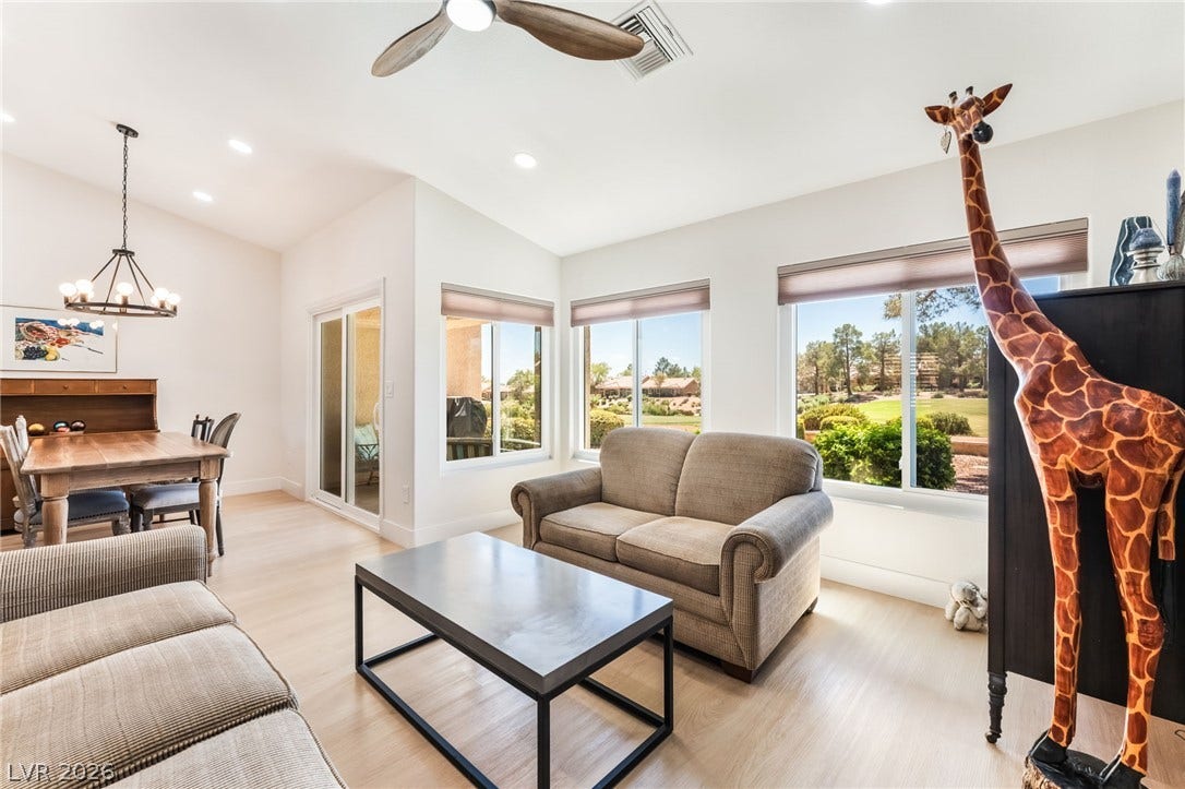 A light-filled living area integrates seamlessly with the dining space over smooth wood-style flooring.