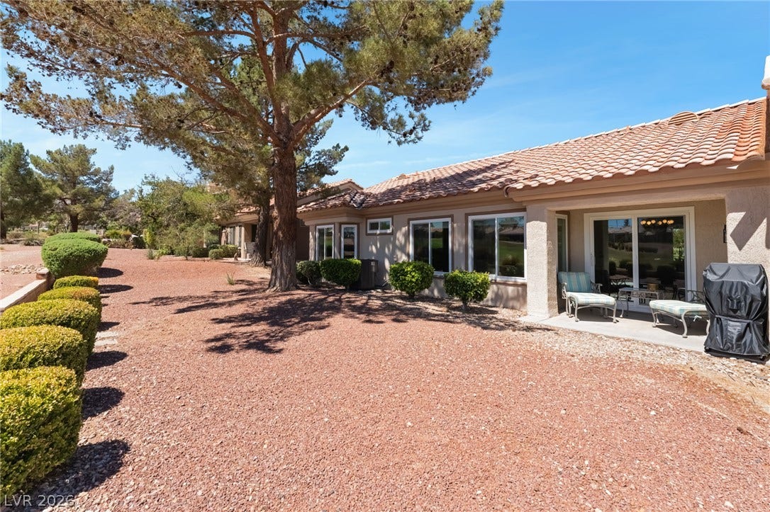 A tiled roof and stucco exterior frame the shaded backyard patio of this classic desert home.