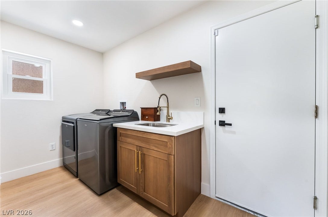 An organized laundry room offers a dedicated utility sink alongside modern wood flooring.